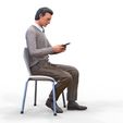 ManSitiing_1.12.116.jpg A Man sitting on a chair with smartphone